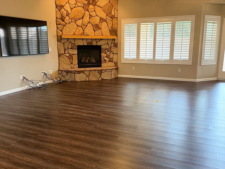 Large open concept living space with gas fireplace; entire home has white polymer shutters