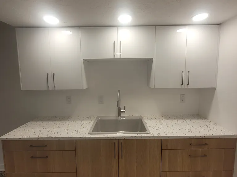 Bright brand new kitchen with quartz countertops and recessed lighting.
