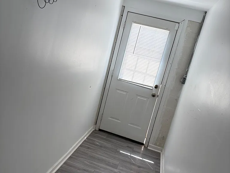 Narrow entry hallway with durable tile flooring and a door with built-in blinds for privacy and natural light.