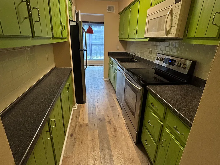 Galley Kitchen with new (2025) dishwasher, white backsplash tile, newer stove (electric) and full size refrigerator.