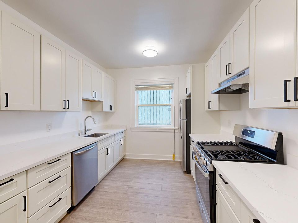 Kitchen with multiple cabinets, refrigerator, stove, range hood, and sink