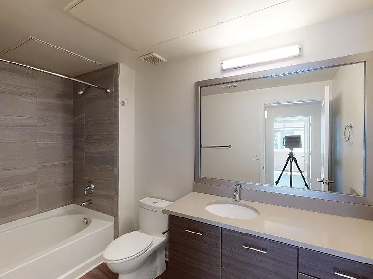 Apartment bathroom with large soaking tub and wood-style flooring.