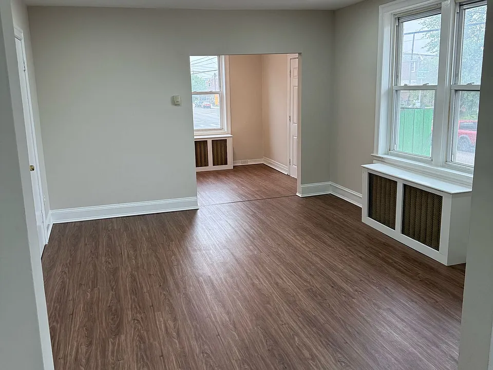 Spacious open living and dining area with updated flooring, recessed lighting, and large windows.