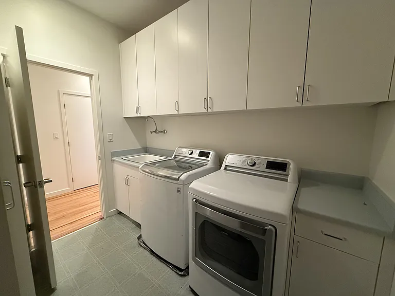 Convenient laundry room includes a utility sink, lengthy countertop and vast amount of storage cabinets.
