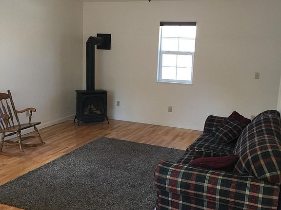 Living room features wooden floor and natural gas stove.