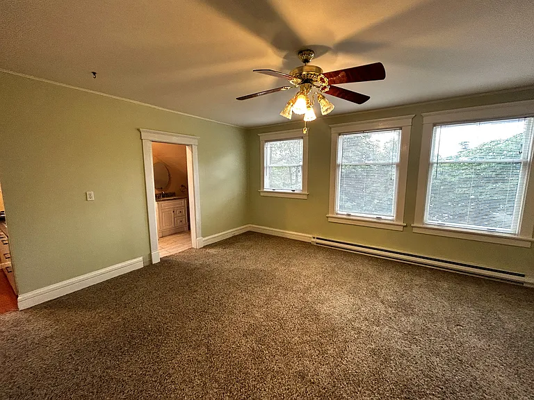 Large newly carpeted and freshly painted living room with plenty of sunny windows.