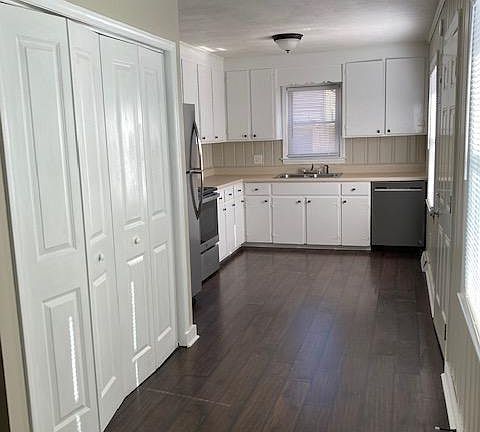 Kitchen with new stainless-steel fridge, dishwasher, range and range hood. Large laundry closet seen on left in photo.