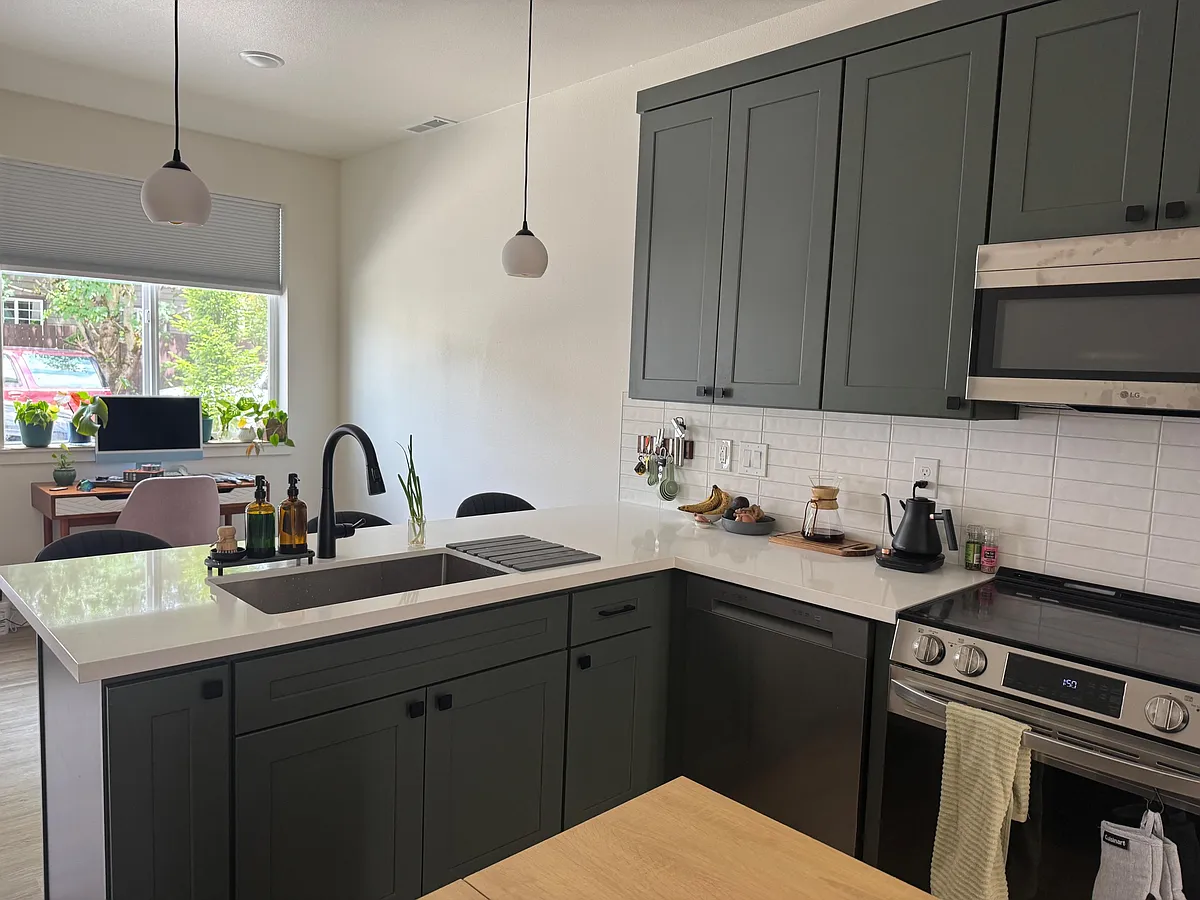 New kitchen with shaker cabinetry, quartz-look counters, tile backsplash, and stainless appliances plus island seating. - NE Couch St