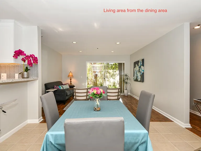 Living area with view of the dining area next to the kitchen. Kitchen counter offers overhang for breakfast nook.