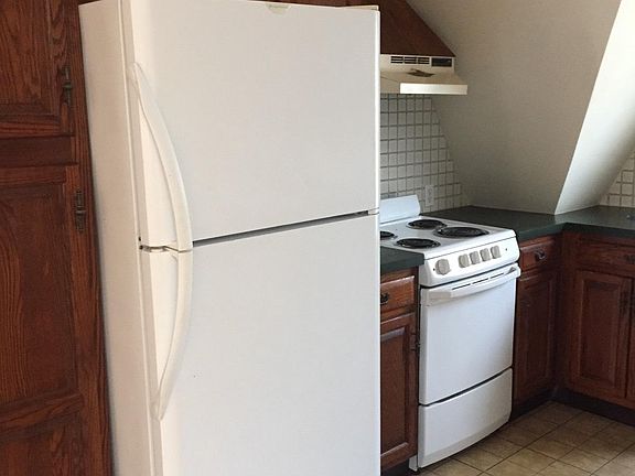 Kitchen fridge and stove and more cabinets.