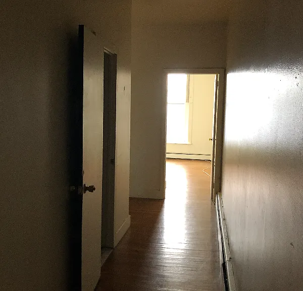 The hallway as you enter the unit. Main bedroom is immediate left, bathroom is off the hallway. Second bedroom is pictured at the end of the hall, followed by the kitchen around the corner.