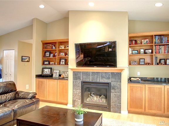 Open living space with vaulted ceilings, gas fireplace, surrounded by custom built-ins.