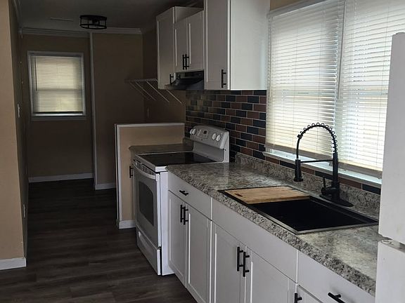 Practical kitchen featuring classic wooden cabinetry, generous counter space, and natural lightperfect for daily cooking.