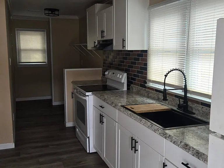 Practical kitchen featuring classic wooden cabinetry, generous counter space, and natural lightperfect for daily cooking.