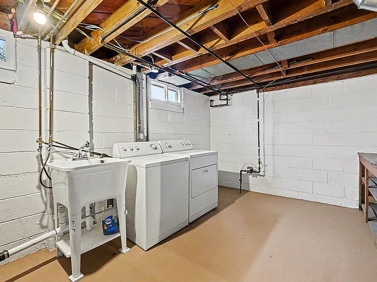 Washer and dryer in clean basement area with newly painted floor and walls.