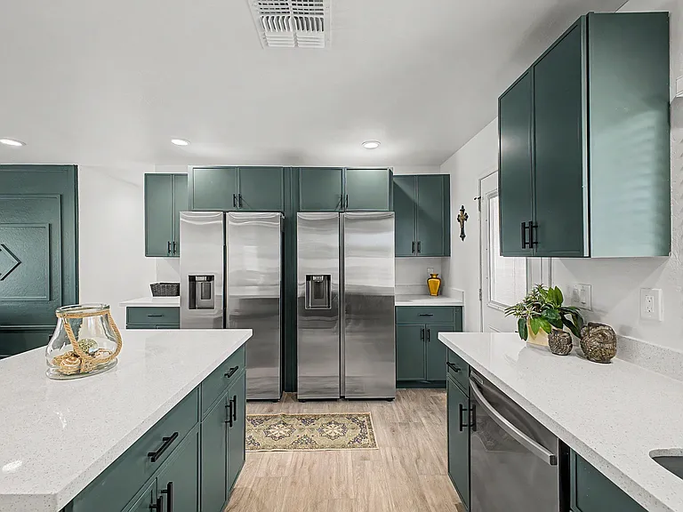 Updated kitchen with expansive quartz counters, generous cabinet storage, and side-by-side stainless refrigerators.