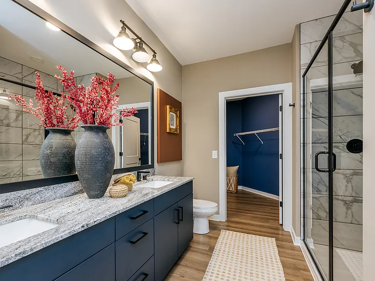 Elevated bathrooms with double vanities and Carrera-inspired tiled showers