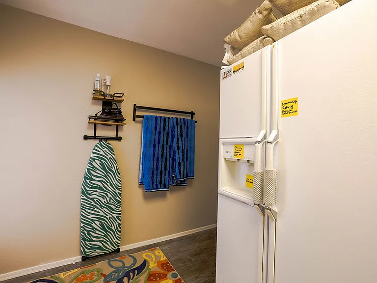 Laundry room with community fridge and iron board