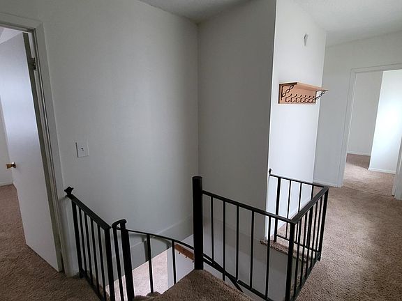 Upstairs hallway showing first bedroom (the one with laundry hook-ups), stairway, second bedroom entrance (around corner) and third bedroom entrance at the end of the hallway. Photo taken from front door.