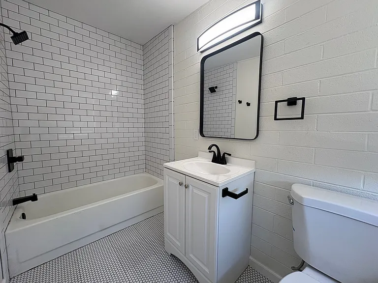 Bathroom with shower / tub combo, new penny tile and subway tile, toilet and vanity.