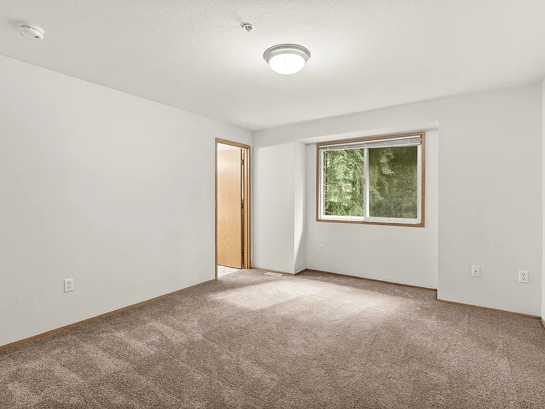Bright and roomy bedroom featuring soft carpeting, natural light, and easy access to the bathroom. Bright and roomy bedroom featuring soft carpeting, natural light, and easy access to the bathroom.