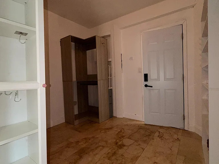 Entry foyer with durable tile flooring, overhead lighting, and built-in shelving plus a storage cabinet near the stairs.