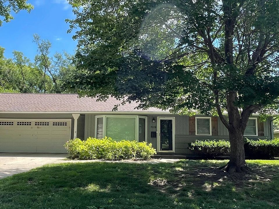 Nicely landscaped front yard with oversized two-car garage and floor-to-ceiling bay window that opens views to a quiet, tree-lined neighborhood street.