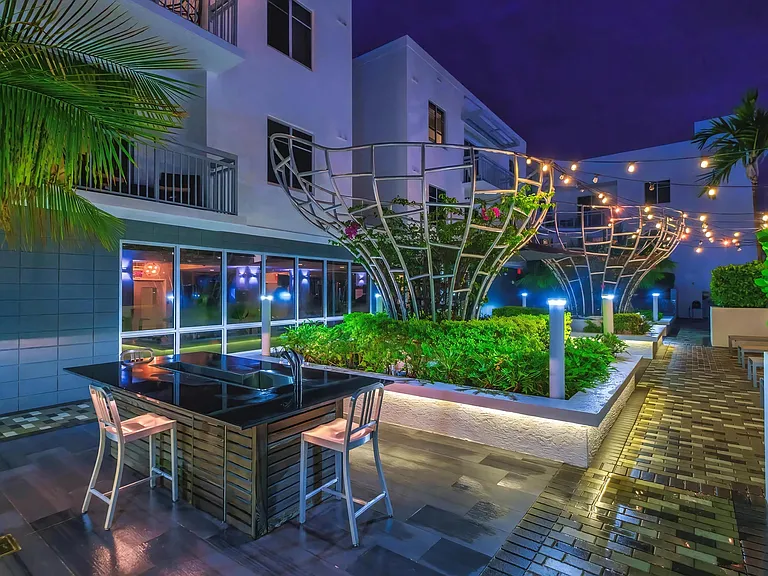 Lit Patio Lounge Featuring Greenery and Sculptural Elements at South of Atlantic