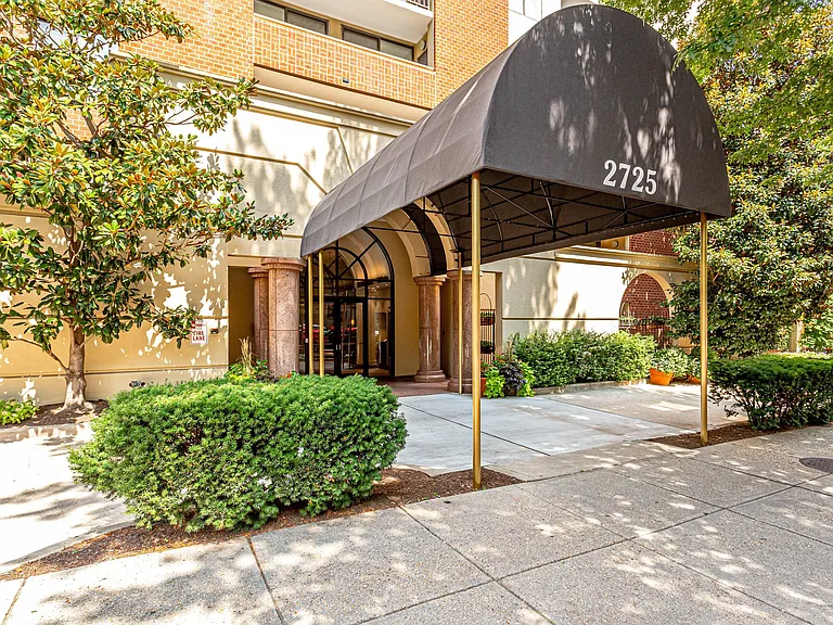 Welcoming, well-maintained building entrance with a classic canopy and lush landscaping