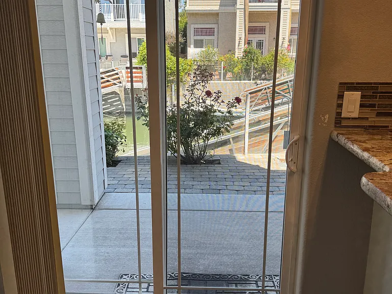 Glass sliding doors open onto paver patio with private dock.