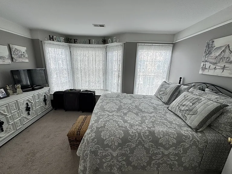 Sun filled bedroom with lots of windows, built in window seat with storage, upper shelves and picture frame molding.