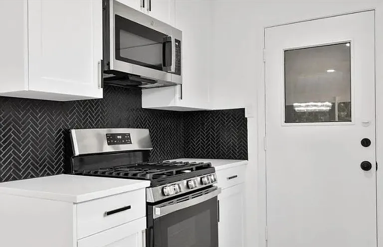 Gas stove with griddle, oven and microwave on top.