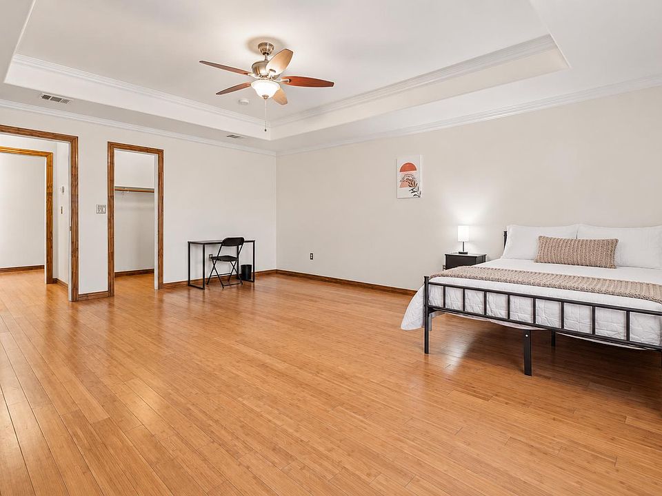 Spacious bedroom with hardwood floors, a ceiling fan, open closet storage, and room for a desk or seating area.