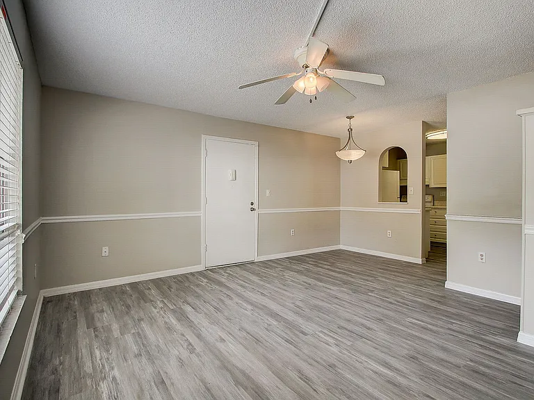 Bright and airy living space with elegant wood flooring, modern ceiling fan, and chic pendant lighting.