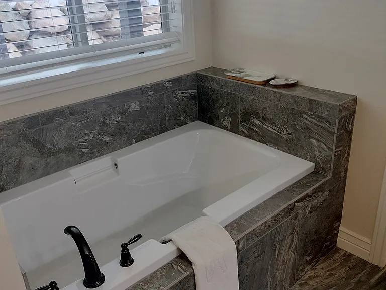 Spacious master bathroom with double sinks, a glass shower, and a large deep tub_perfect for relaxing after a long day. Designed for comfort and style, this serene retreat offers the ultimate in convenience and luxury.