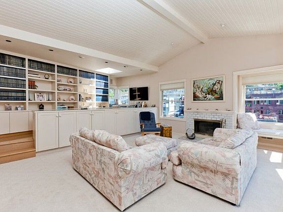The grand living room overlooks the water. It’s windows welcome gorgeous light. It’s balcony welcomes breezes. Its adjoining library is set at an dynamic angle w/built-in cabinets, desk & corner windows.
