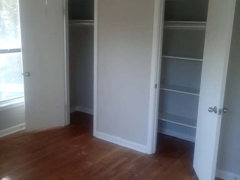 2nd bedroom with original hardwood flooring, remodeled, with double closets and ceiling fan.
