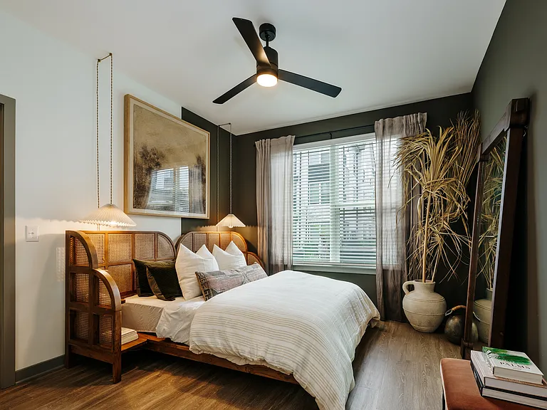 Elegant apartment bedroom with wood-inspired plank flooring, oversized windows, ceiling fan, and designer finishes.