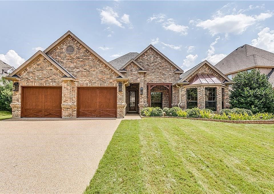 Front of house features cedar garage doors, gas lantern coach lights, copper roof, cedar post accents, and custom brick work.