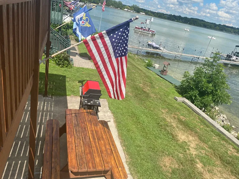 Looking north. Pic nic table and gas grill on the cement slab below the deck on the front lawn