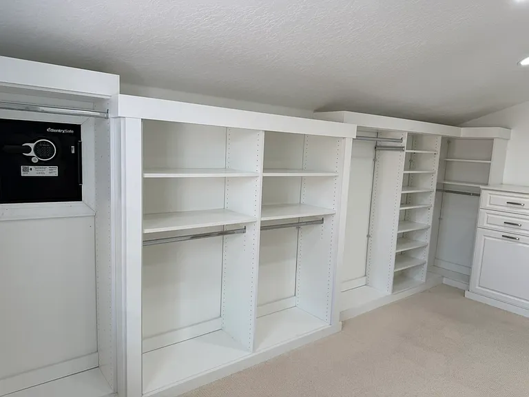 Primary closet with safe and numerous shelves and systems for clothes storage