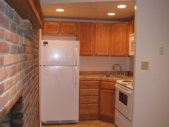 very small corner kitchen with full size range/oven, microwave oven and refrigerator and quite a few cabinets.