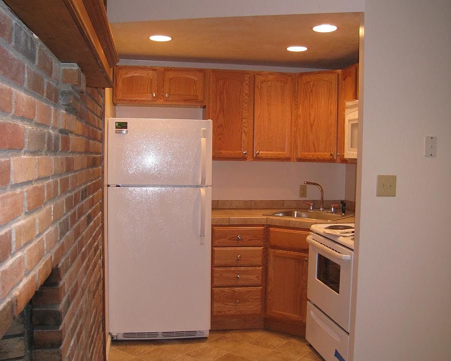 very small corner kitchen with full size range/oven, microwave oven and refrigerator and quite a few cabinets.