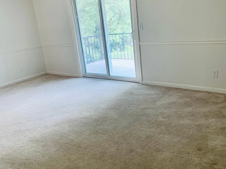 Large living room space with crown molding finishes. Accesses patio that overlooks spacious lawn. Easy access to lawn from side door outside of unit.