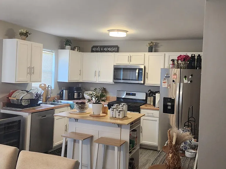 Open kitchen with ample white cabinetry, stainless appliances, and a center island with seating for casual meals.