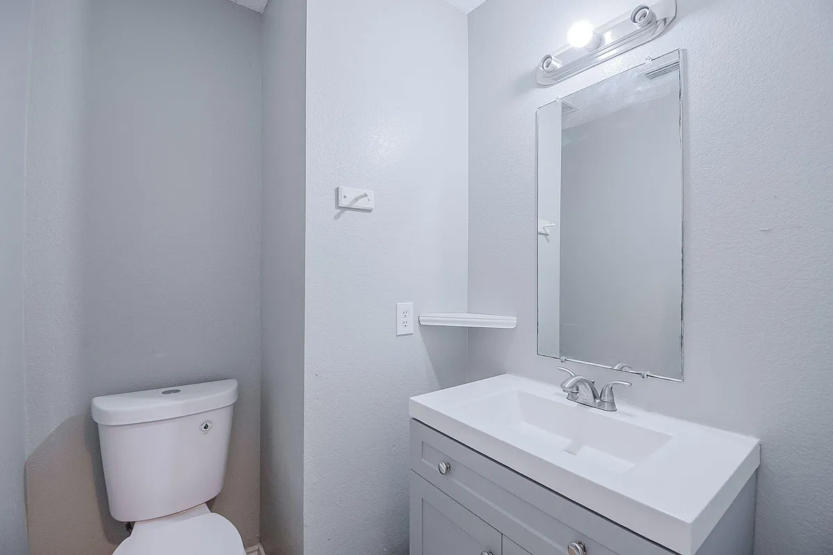Bathroom with a single-sink vanity, wall mirror, and overhead lighting, plus space for daily essentials. - W Grove Ln