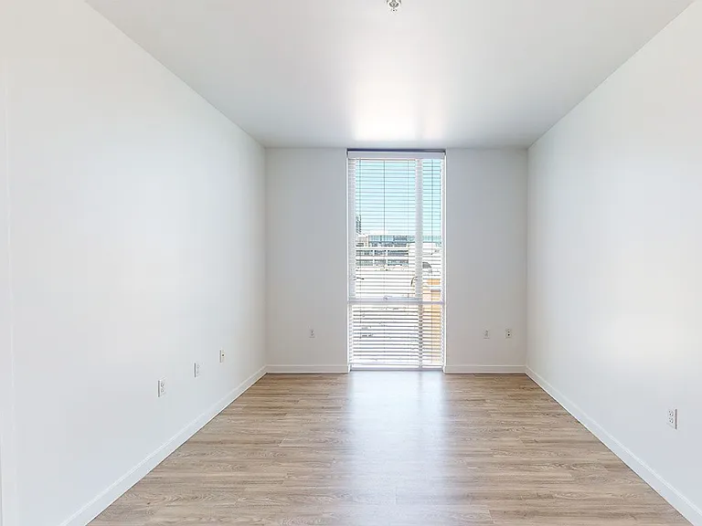 Apartment living room with wood-style flooring and floor-to-ceiling windows.