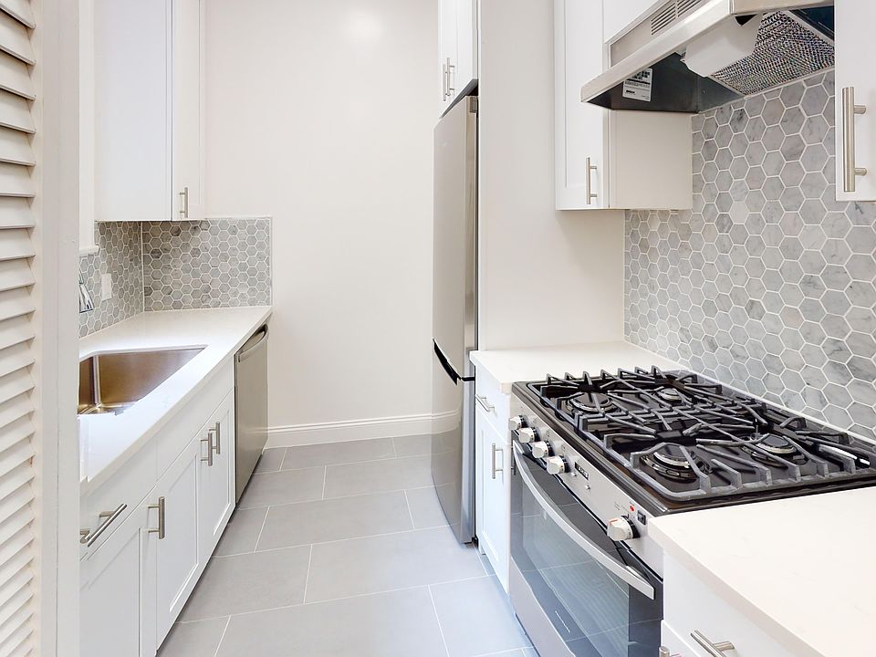 Kitchen with multiple cabinets, refrigerator, stove, range hood, and sink