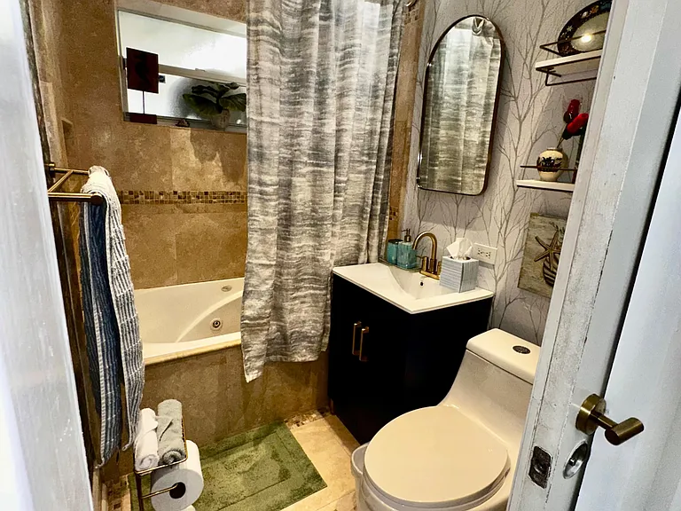 Full bathroom with tub/shower combo, vanity sink, and built-in wall shelving for everyday storage and essentials.