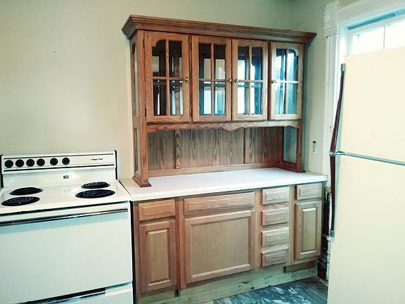Decorative wooden cabinets here and over the kitchen sink give this kitchen style. There is a window on the north wall, which does not show in this picture. Stove, refrigerator, washer and dryer are furnished. A door to the left of the stove gives acces